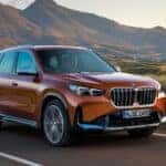 An orange 2025 BMW X1 for sale from the front at an angle.