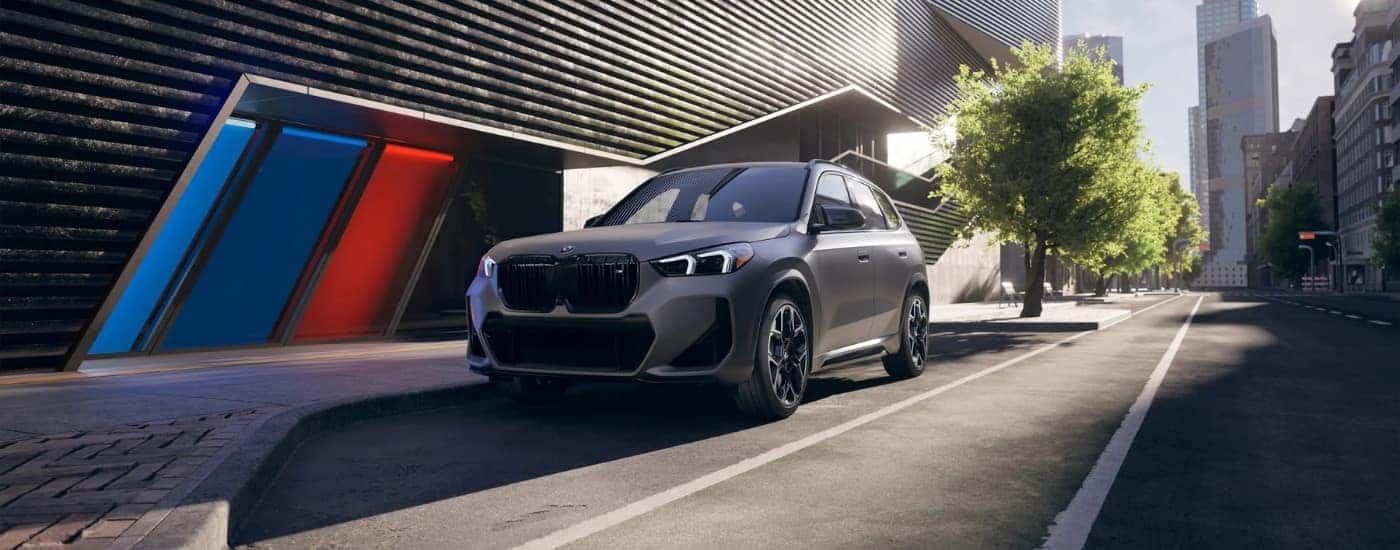 A grey 2026 BMW X1 M35i parked in front of a building.