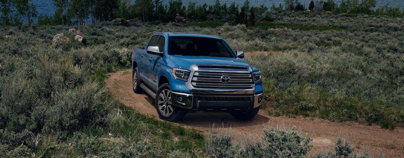 A blue 2021 Toyota Tundra from a Toyota dealer near you is driving on a dirt train in front of a river.