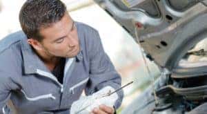 A mechanic is performing an oil change near you by examining the dipstick.