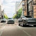 Three 2021 Toyota RAV4s are driving on a multi-lane city street.