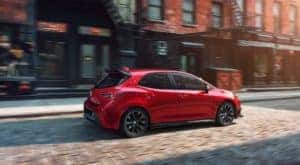 A red 2021 Toyota Corolla Hatchback from a Toyota dealer near you is driving on a cobblestone road.