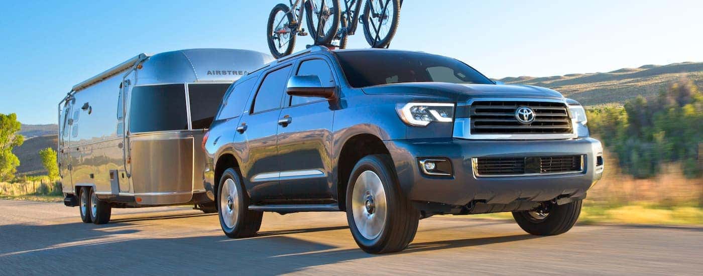 A grey 2021 Toyota Sequoia is towing an Airstream and has bikes on the roof rails.