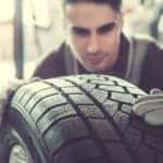 A technician is looking closely at a tire at a tire shop near me.