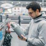 A man is holding a jug of oil at the store.