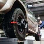 A mechanic is aligning the tires on a vehicle.
