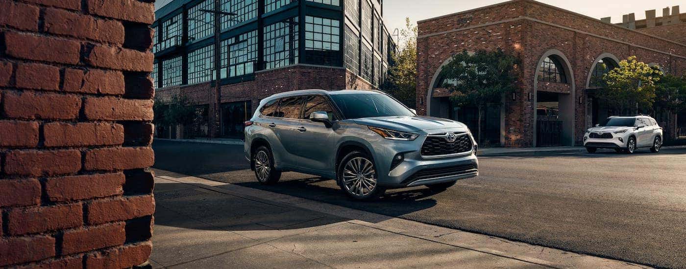 A silver 2021 Toyota Highlander Hybrid is parked on a city street.