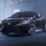 A black 2021 Toyota Camry Hybrid SE Nightshade Edition is parked in an empty warehouse.