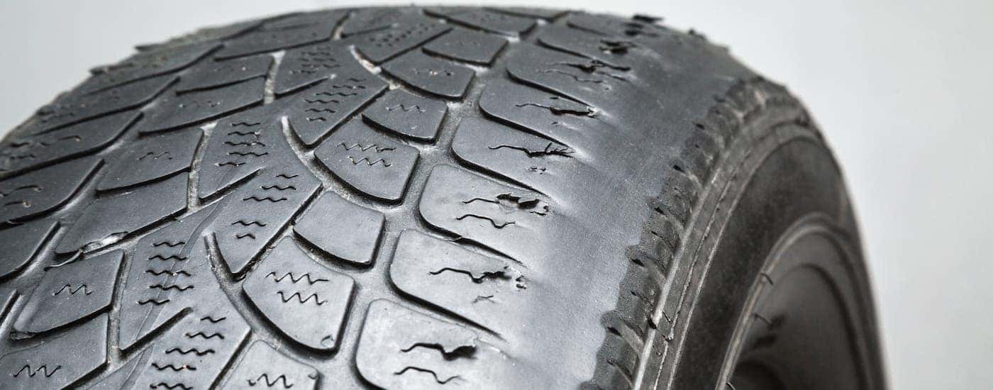 A tire with irregular wear is shown against a light gray background.