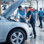 A mechanic and sales person are looking under the hood of a car at a Toyota service department.