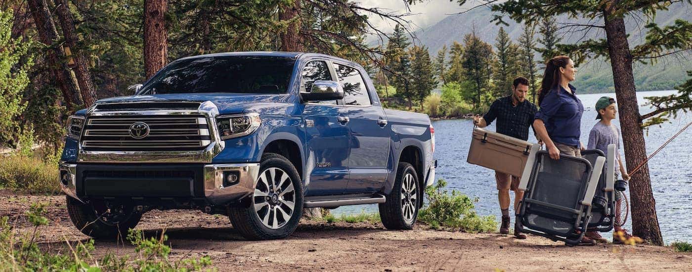 A family has fishing gear at a lake next to a blue 2021 Toyota Tundra.