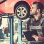 A mechanic is inspecting a certified pre owned Toyota on a lift.