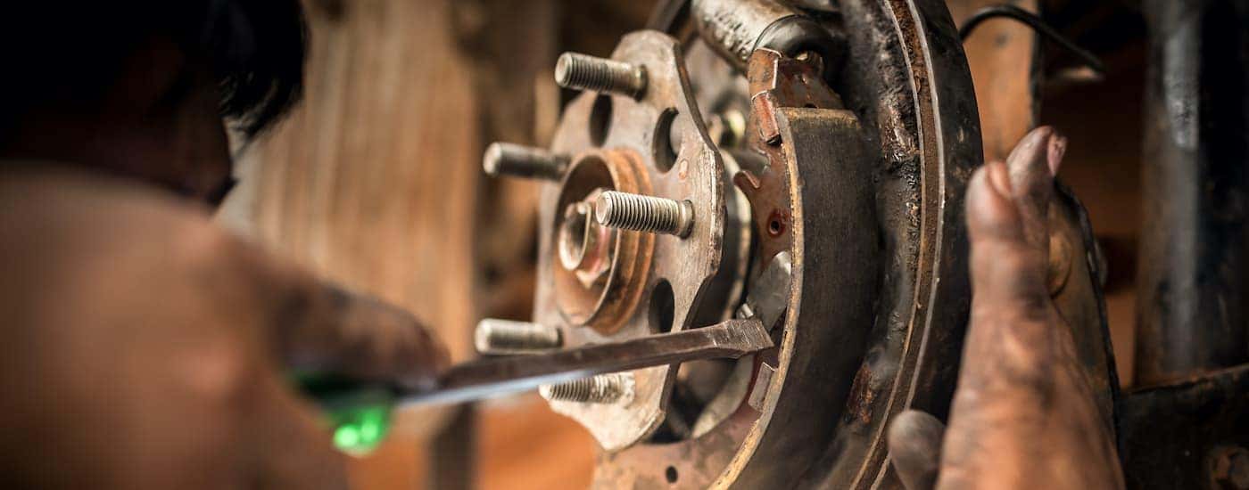 A close up is showing a retaining clip being removed with a screwdriver on drum brakes.