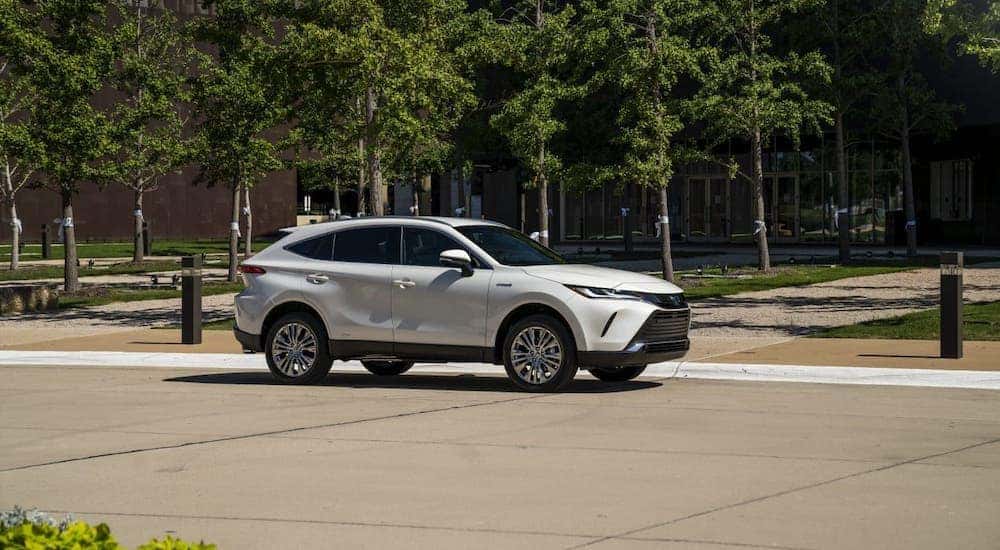 A white 2021 Toyota Venza is parked in front of trees and buildings.
