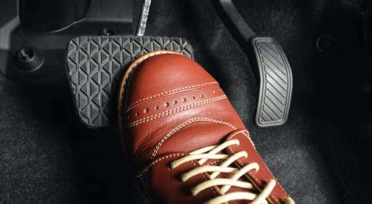 A close up shows a shoe on a brake pedal.