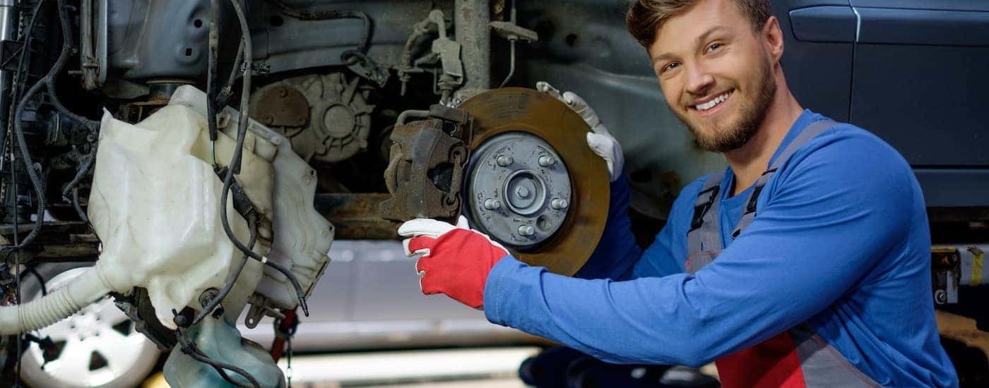 A mechanic is smiling and holding a rotor during a Toyota brake service.