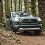 A Lunar Rock 2021 Toyota RAV4 is driving through the woods after leaving the Toyota RAV4 dealer.