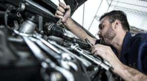 A mechanic is shown working in an engine bay during a Toyota Sienna service.