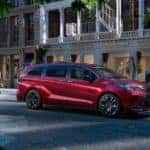 A red 2021 Toyota Sienna is driving through a city.
