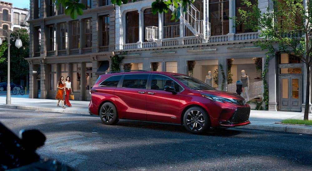 A red 2021 Toyota Sienna is driving through a city.