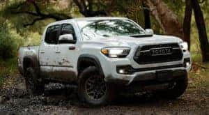 A white 2021 Toyota Tacoma is off-roading in mud after leaving a Toyota Tacoma dealer.