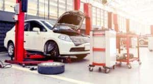 A white car is on a lift for a full auto service.