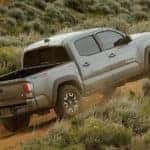 A grey 2021 Toyota Tacoma is driving up a dirt hill after leaving a Toyota Tacoma dealer.