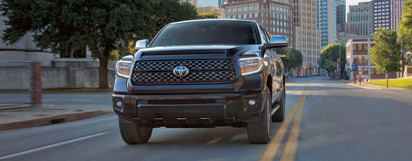 A black 2021 Toyota Tundra is shown from the front driving through a city.