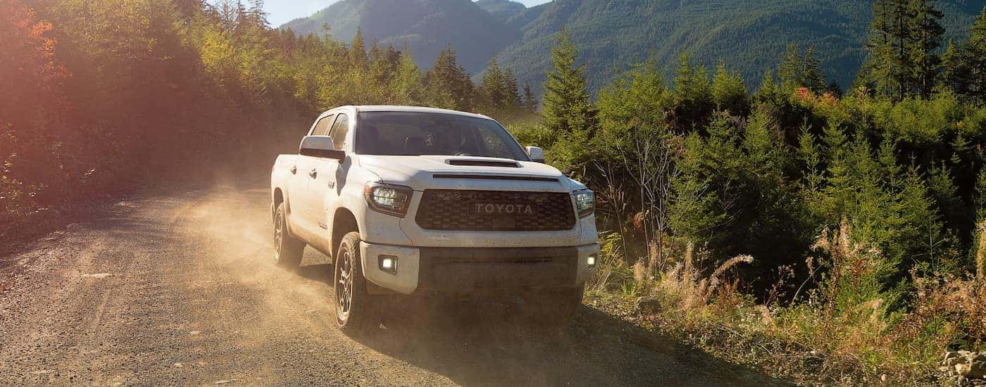 A white 2021 Toyota Tundra is driving down a dirt road after leaving a Toyota Tundra dealership.
