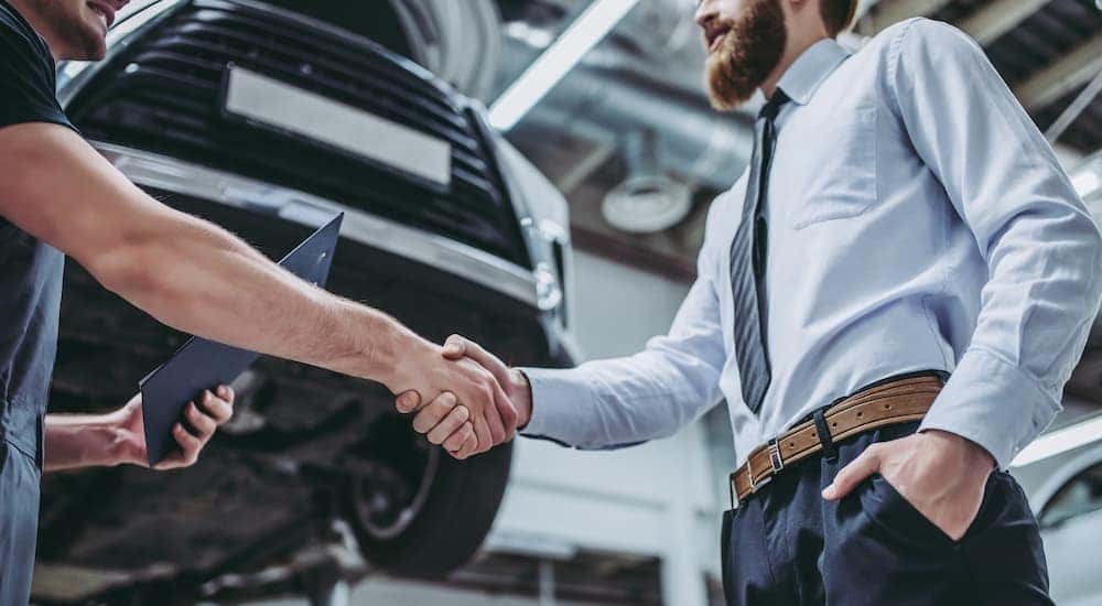 A mechanic is shaking hands with a man at an affordable auto service.