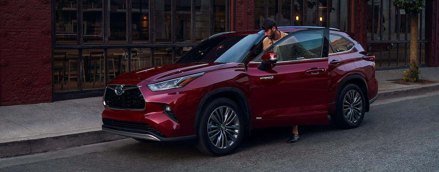 A man is shown getting into a burgundy 2021 Toyota Highlander Hybrid.