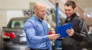 Two men are looking a clipboard during an affordable auto service.