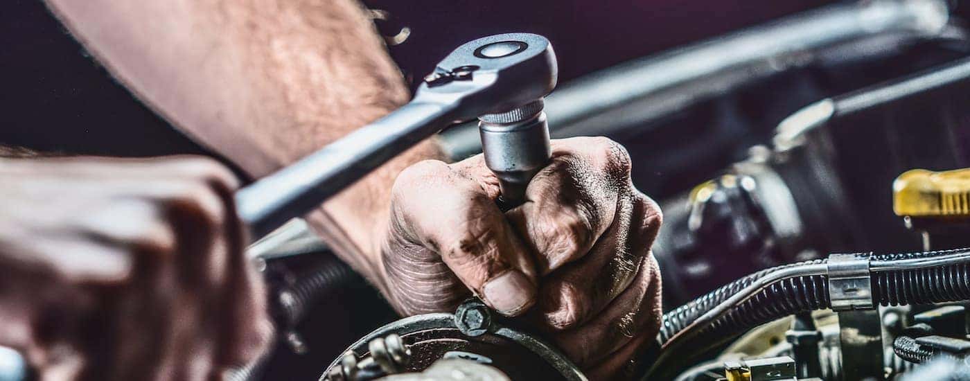 A mechanic is shown using a socket wrench during an affordable auto service.