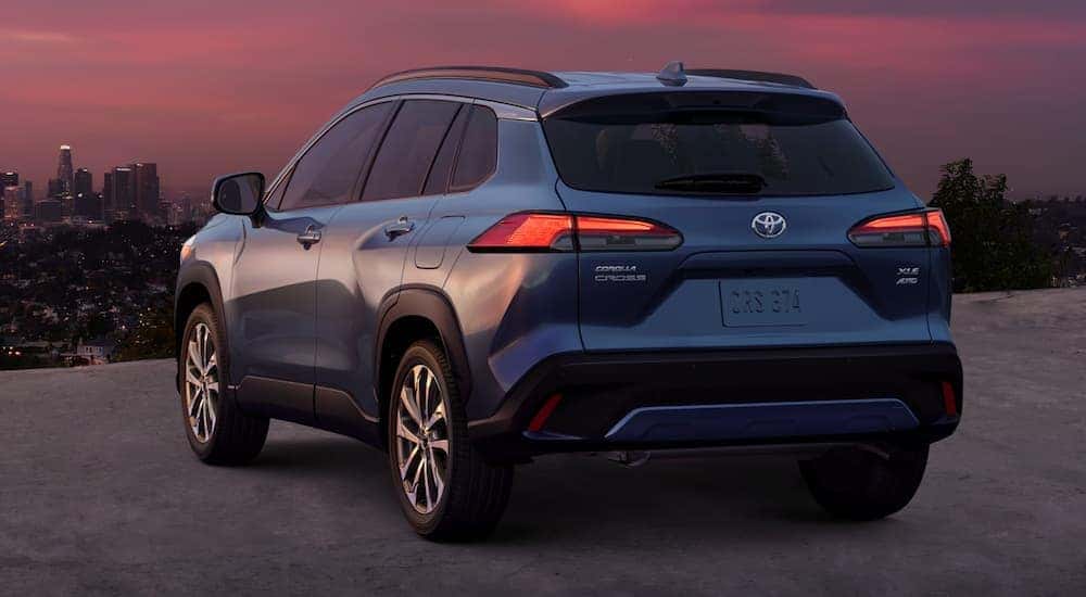 A blue 2022 Toyota Corolla Cross XLE AWD is shown from the rear parked at sunset.