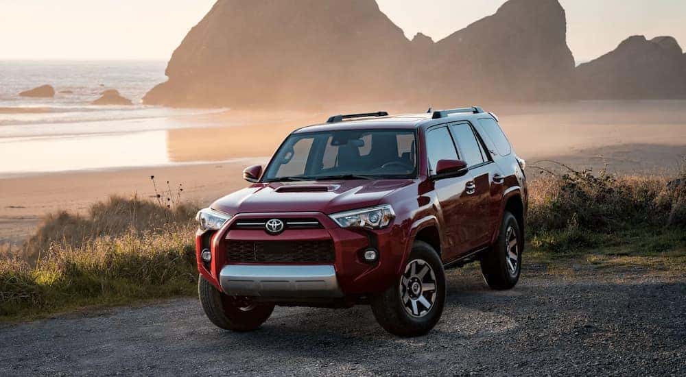 A red 2022 Toyota 4Runner is shown parked by the ocean near a Toyota SUV dealer.