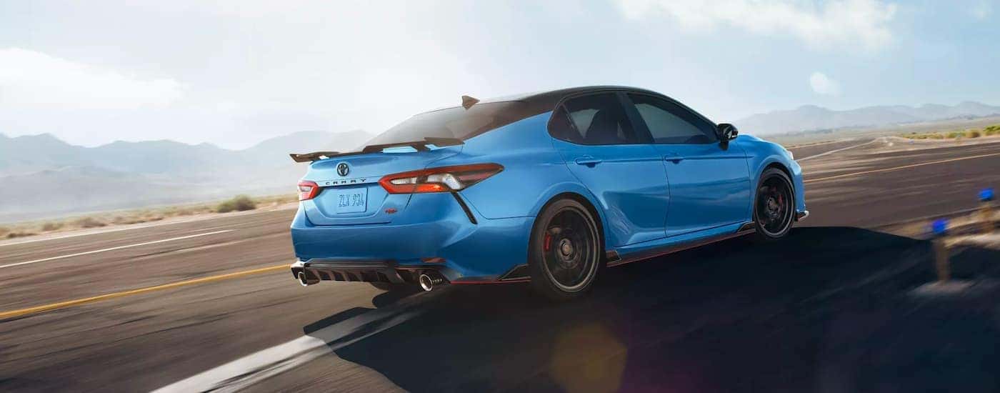 A blue 2022 Toyota Camry TRD is shown from the side driving on a racetrack.