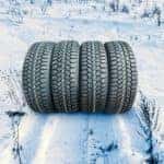A set of four tires are shown in the snow.