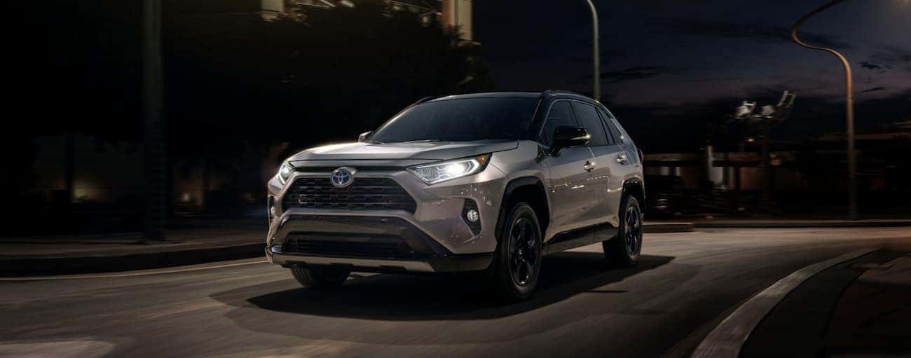A silver 2020 Toyota RAV4 is shown driving on a city highway at night.