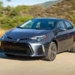 A grey 2018 Toyota Corolla is shown driving on a dirt road after leaving a certified pre-owned Toyota dealer.