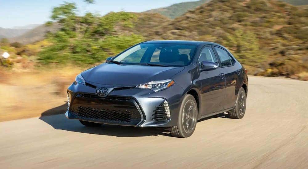 A grey 2018 Toyota Corolla is shown driving on a dirt road after leaving a certified pre-owned Toyota dealer.