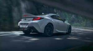 A white 2022 Toyota GR86 is shown from the side speeding down a road.