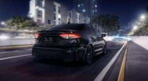 A black 2022 Toyota Corolla SE is shown from the rear driving on an open road.