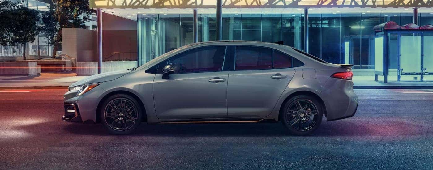 A white 2022 Toyota Corolla SE is shown from the side driving through a city at night.