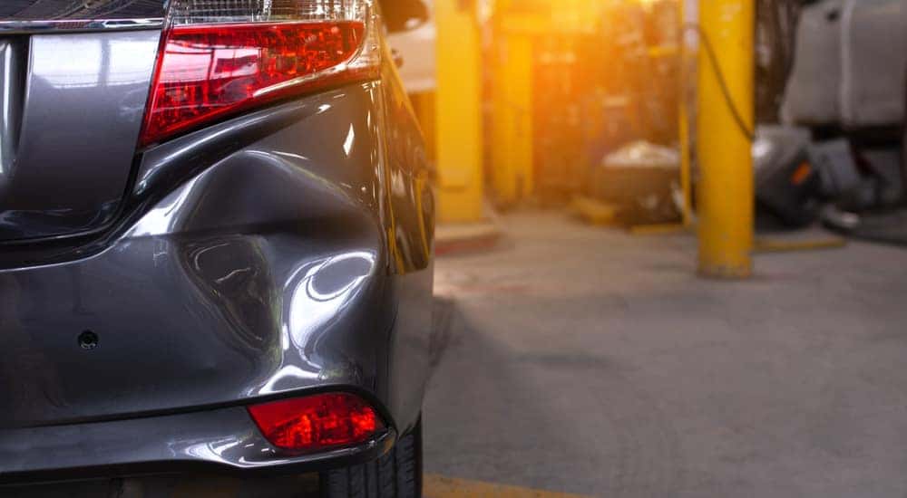 A close up of a dent on a car bumper is shown at a collision repair shop in Romeoville.