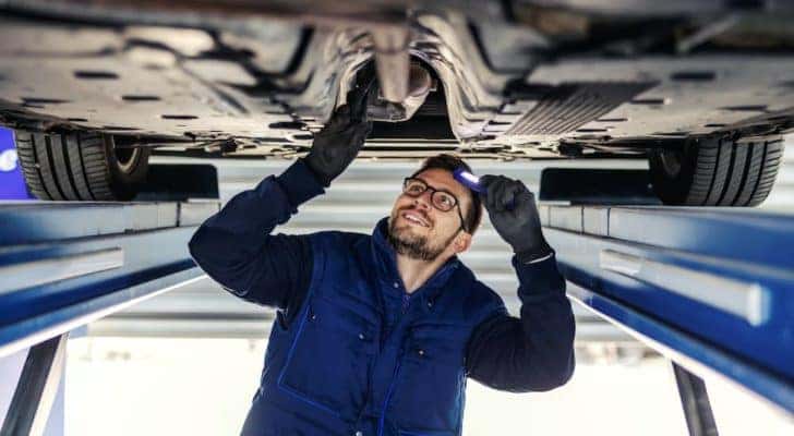 A mechanic is shown examining an exhaust pipe.