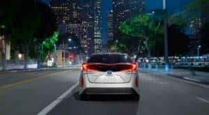 A silver 2022 Toyota Prius Prime LE is shown from the rear driving in a city after leaving a Toyota Prius dealership.