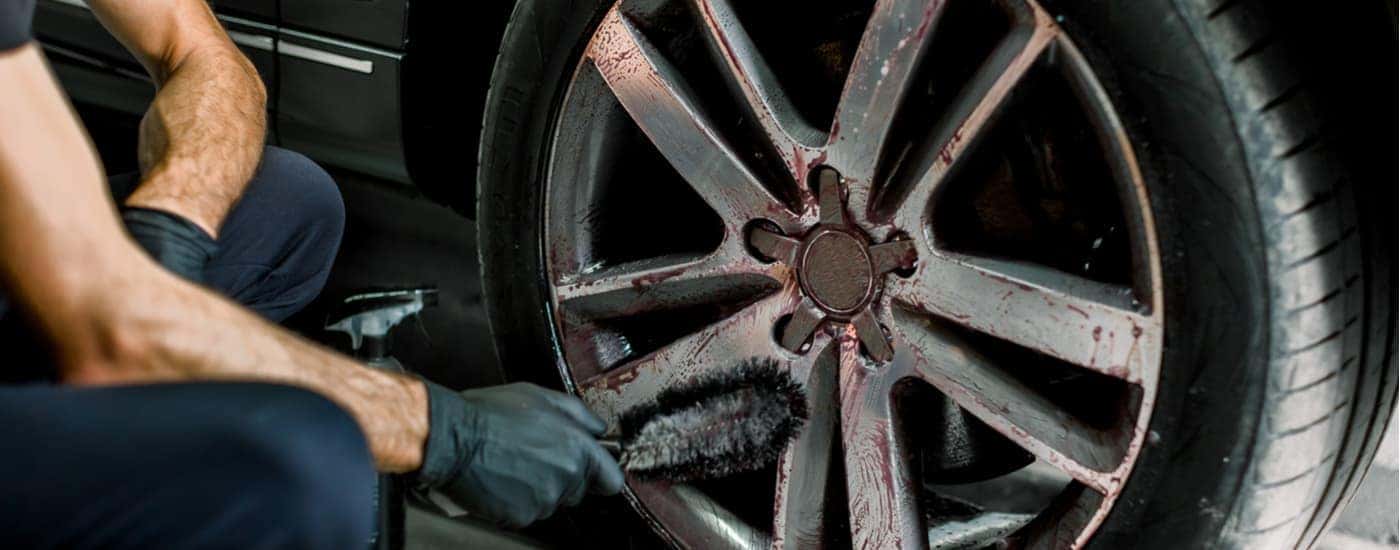 A mechanic is shown cleaning a car rim at an auto collision repair center.