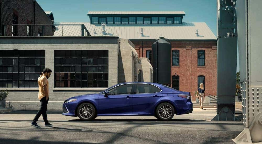 A blue 2022 Toyota Camry XLE is shown from the side parked on a city street.