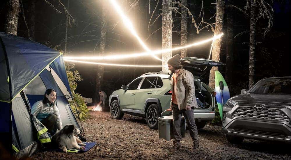 A green and a grey 2022 Toyota RAV4 Adventure Grade are shown at a campsite.