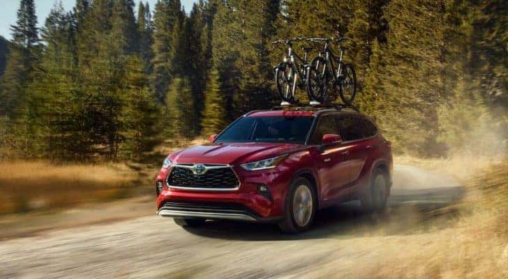 A red 2020 Toyota Highlander Hybrid is shown from the front driving on a dirt road.